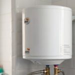 Termo eléctrico doméstico instalado en pared con conexiones de agua y válvula de seguridad visibles