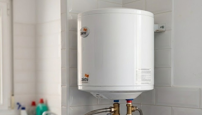 Termo eléctrico doméstico instalado en pared con conexiones de agua y válvula de seguridad visibles