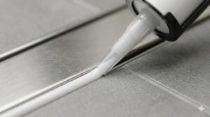 Aplicación de silicona antimoho tras la reparación y sellado de juntas del baño.