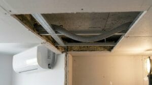 Tubo flexible de desagüe con comba que retiene agua en un falso techo. hay que comprobar que haya caída del desagüe del aire acondicionado