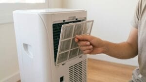 Aire acondicionado portátil en un dormitorio pequeño con salida a ventana