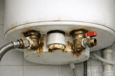 Termo eléctrico con corrosión visible en las conexiones de agua.