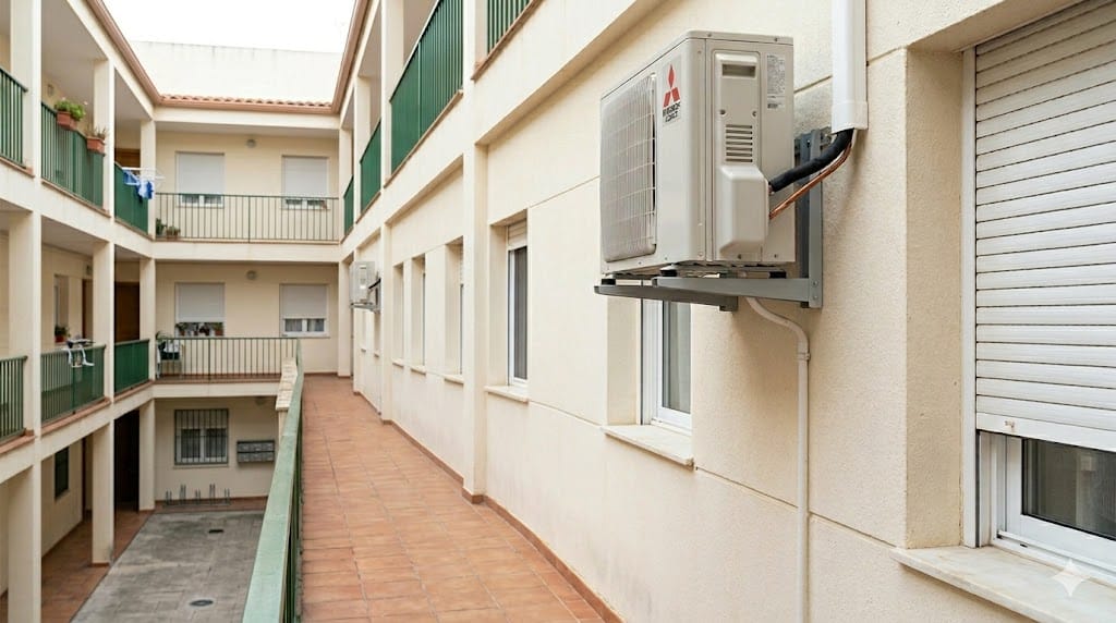 Unidad exterior de aire acondicionado instalada en una fachada de edificio residencial