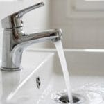 Agua saliendo de forma continua por un grifo de agua caliente al purgar un termo eléctrico.