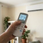 Mando de aire acondicionado con función Turbo activada frente a un split de pared en un salón